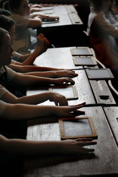 children's hands on desks in classroom